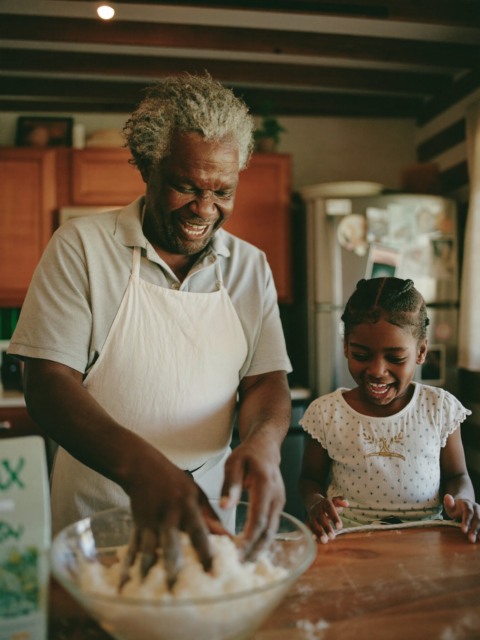 A grandfather and his granddaughter baking together in the kitchen.