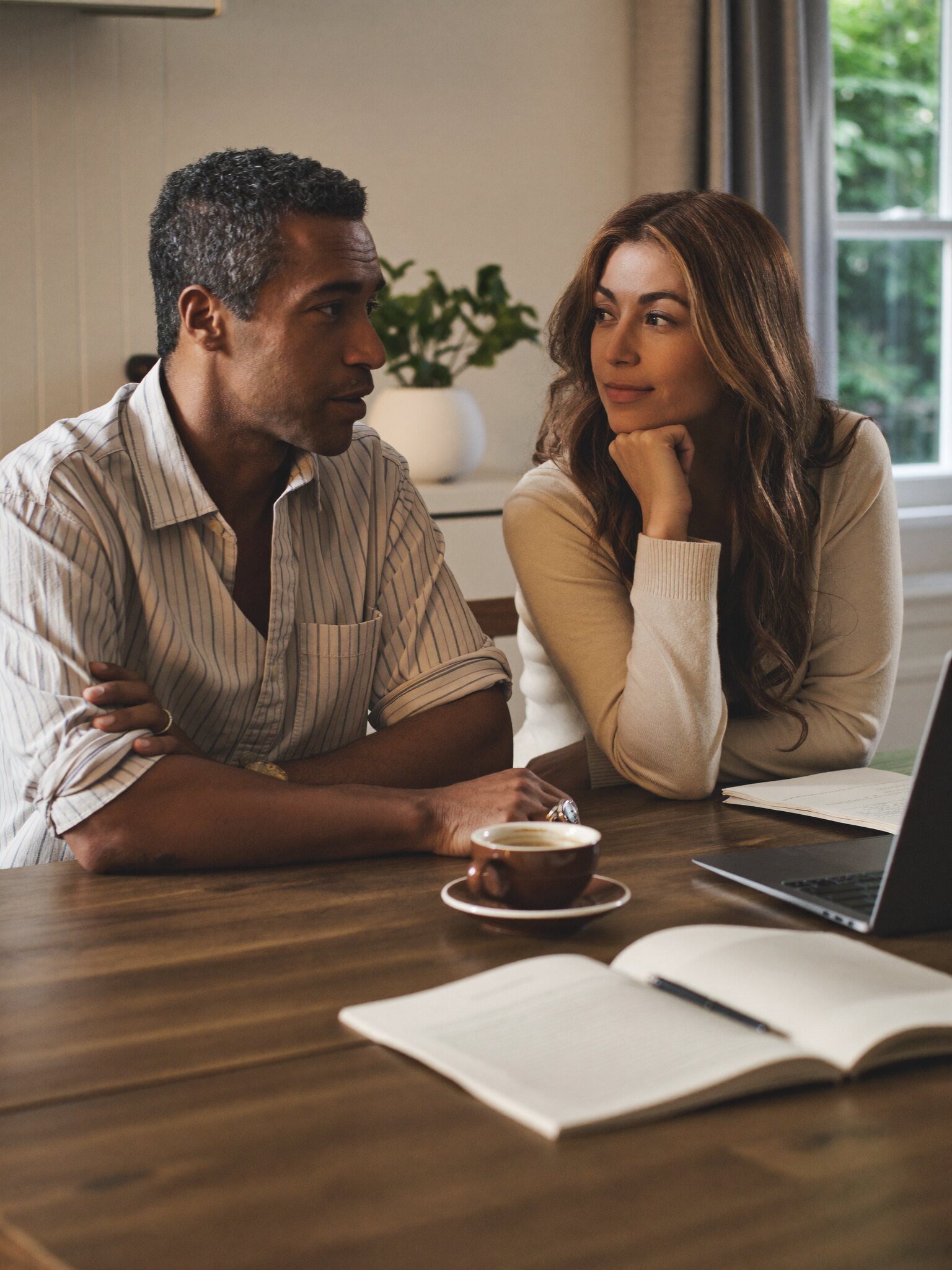 A couple talking over coffee at their kitchen table.